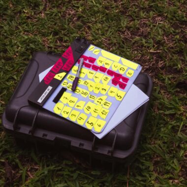 A close-up of a film production slate and suitcase on a grassy lawn.