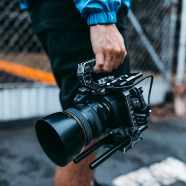 Focused image of a person holding a professional film camera outdoors.
